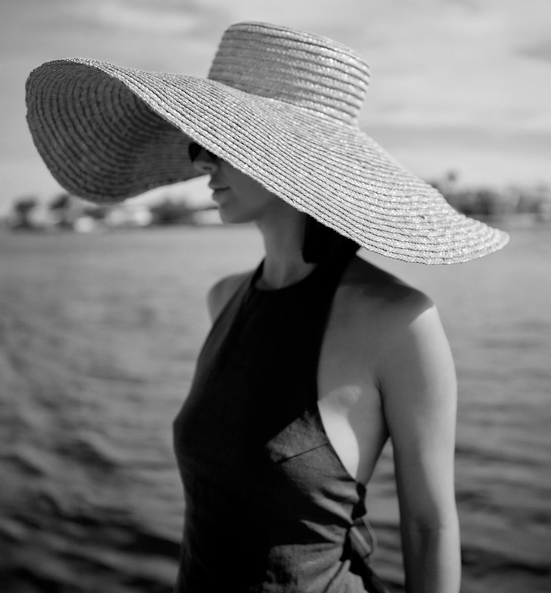 Elegant woman in sunhat standing in front of water